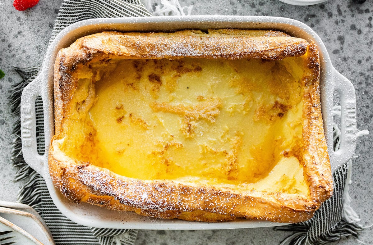 German pancakes in baking dish dusted with powdered sugar. 