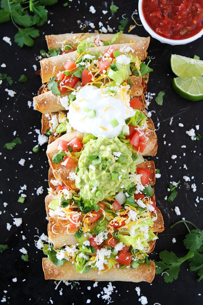 Baked Chicken Taquitos loaded with toppings on pan