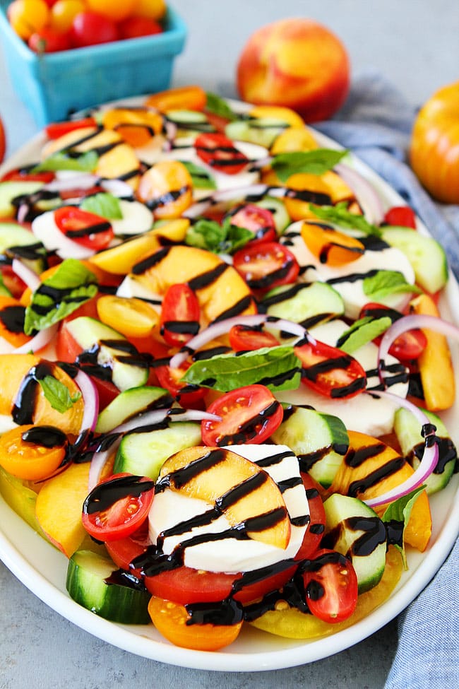 Summer Caprese Salad made with tomatoes, peaches, cucumber, fresh mozzarella cheese, red onion, basil, and a simple balsamic glaze. This easy summer salad is the BEST! 