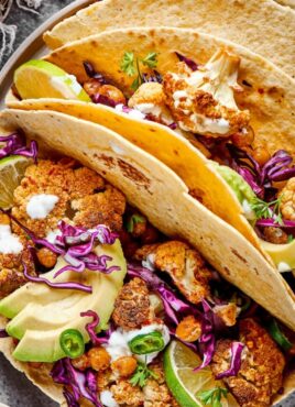 Close up of three roasted cauliflower and chickpea tacos on a plate