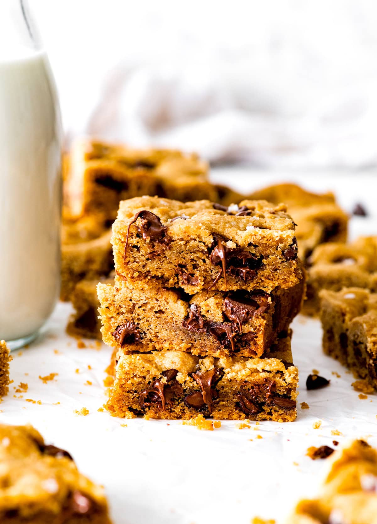 stack of chocolate chip cookie bars with glass of milk. 