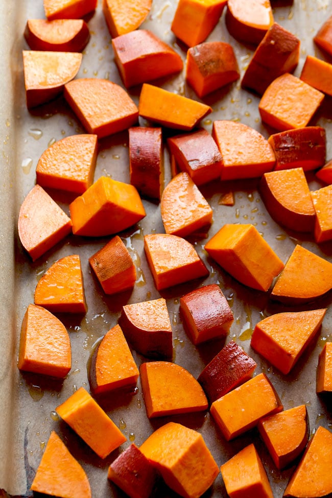 maple drizzles sweet potatoes on baking sheet. 