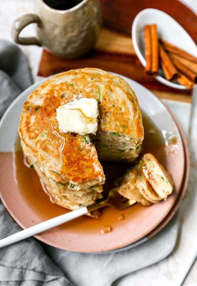 zucchini pancakes with butter and maple syrup on plate with fork