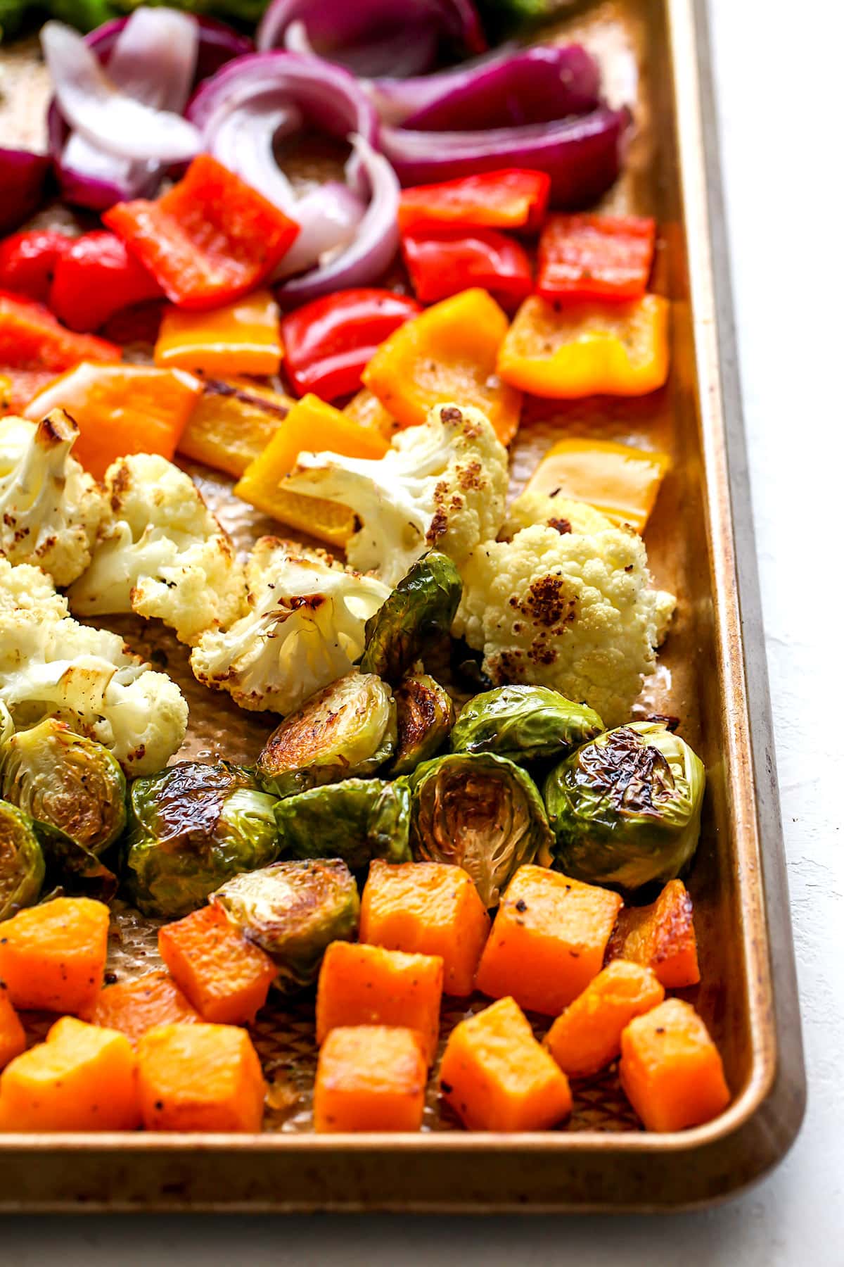 roasted sweet potatoes, brussels sprouts, cauliflower, peppers, and red onion on sheet pan. 