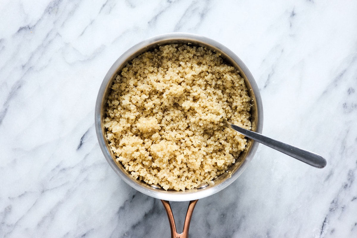 cooked quinoa in pot with fork to fluff it. 