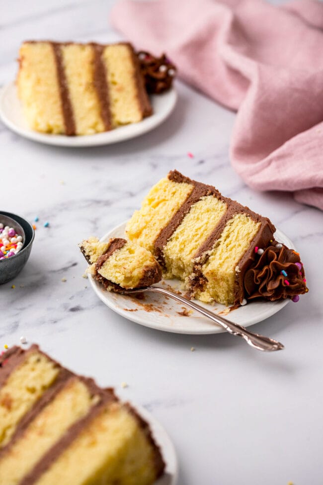 piece of yellow cake with chocolate frosting on a plate with a fork