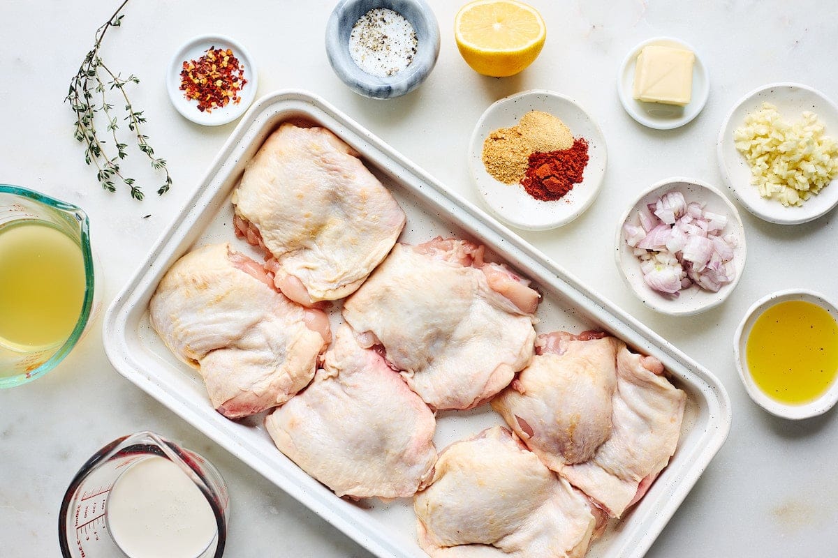 raw chicken thighs on platter and ingredients in bowls to make skillet chicken thighs. 