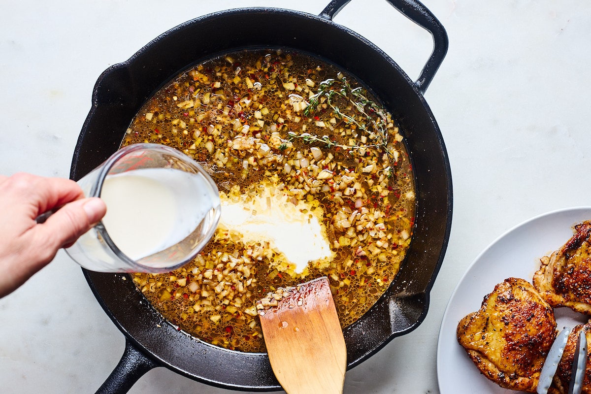 making garlic cream sauce in cast iron skillet for crispy chicken thighs. 