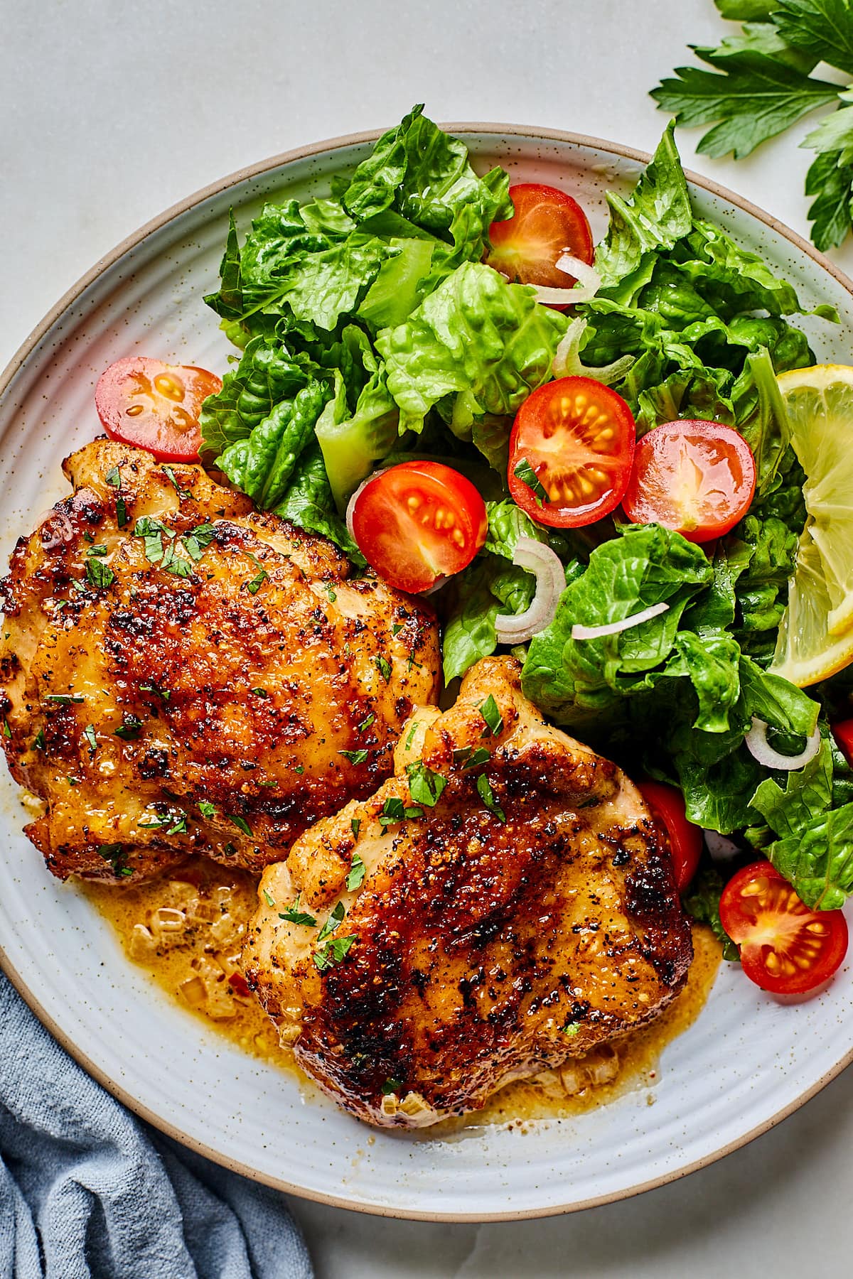 crispy chicken thighs on plate with salad.