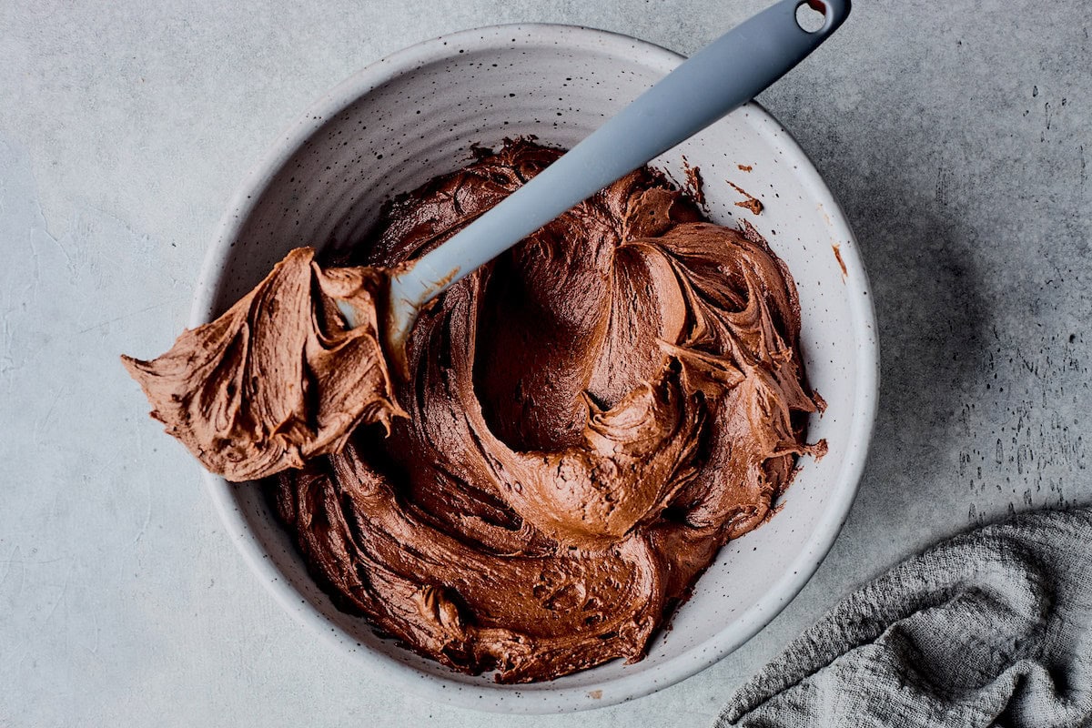 chocolate frosting in mixing bowl with spatula. 