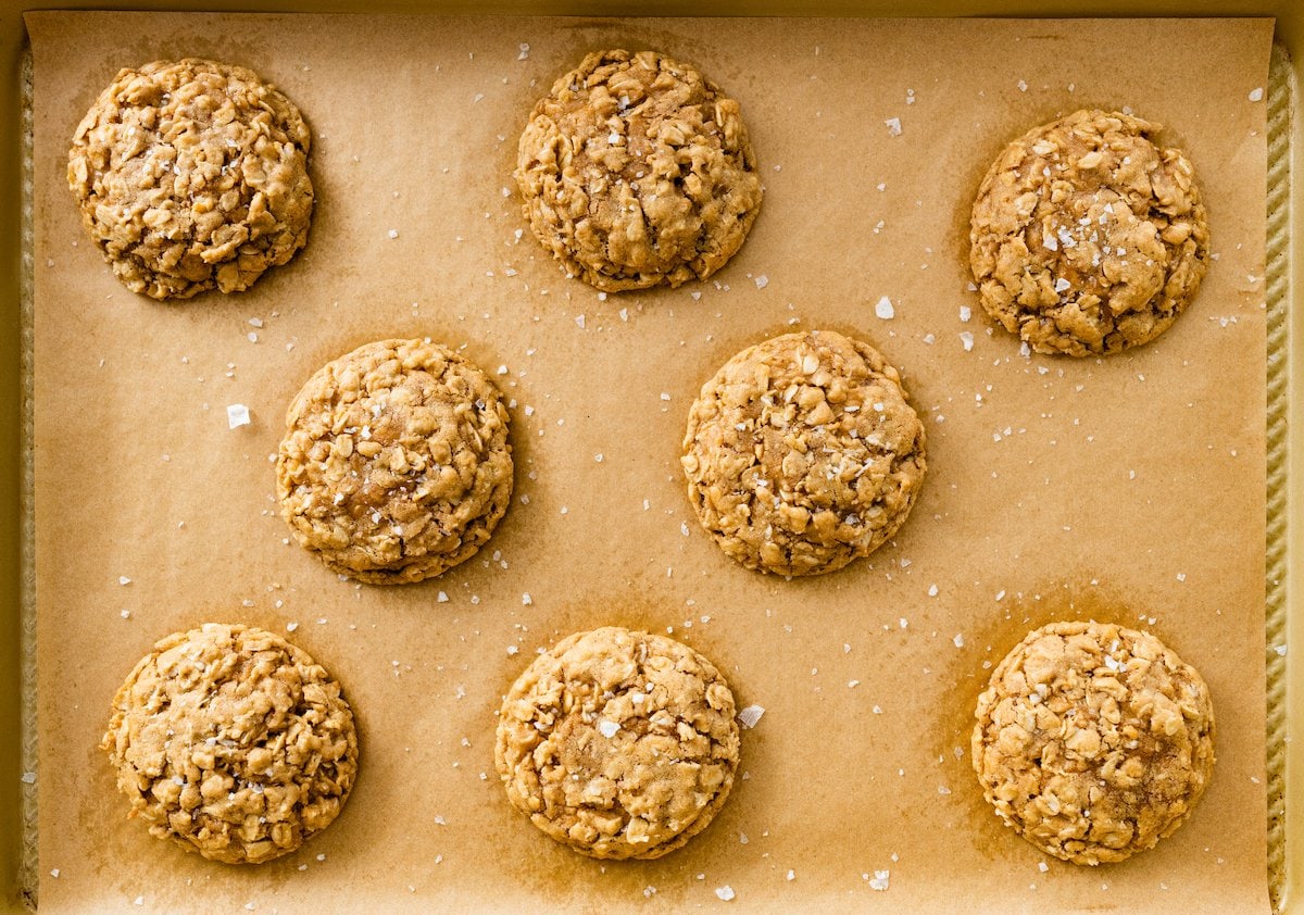 oatmeal cookies with flaky sea salt on baking sheet with parchment paper. 