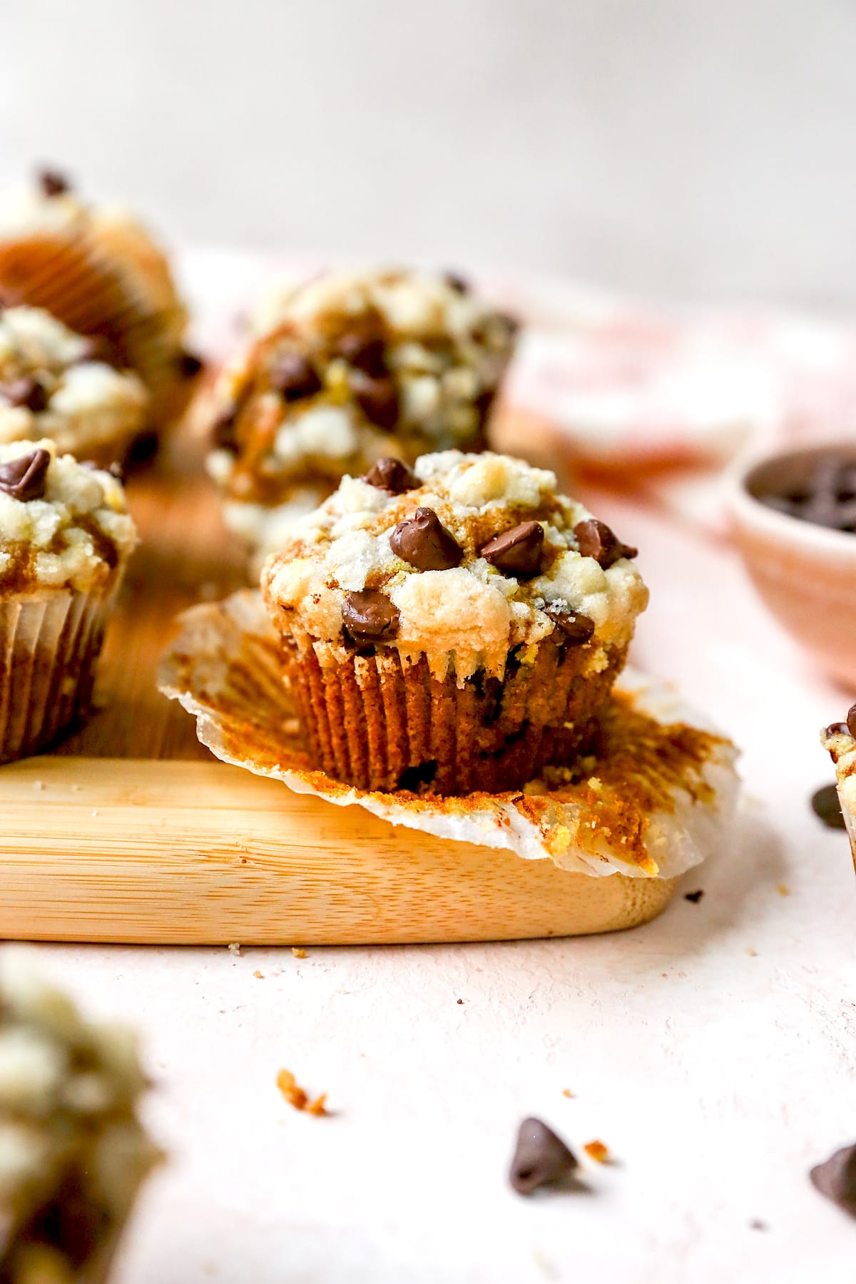 pumpkin chocolate chip muffin unwrapped on wood cutting board. 