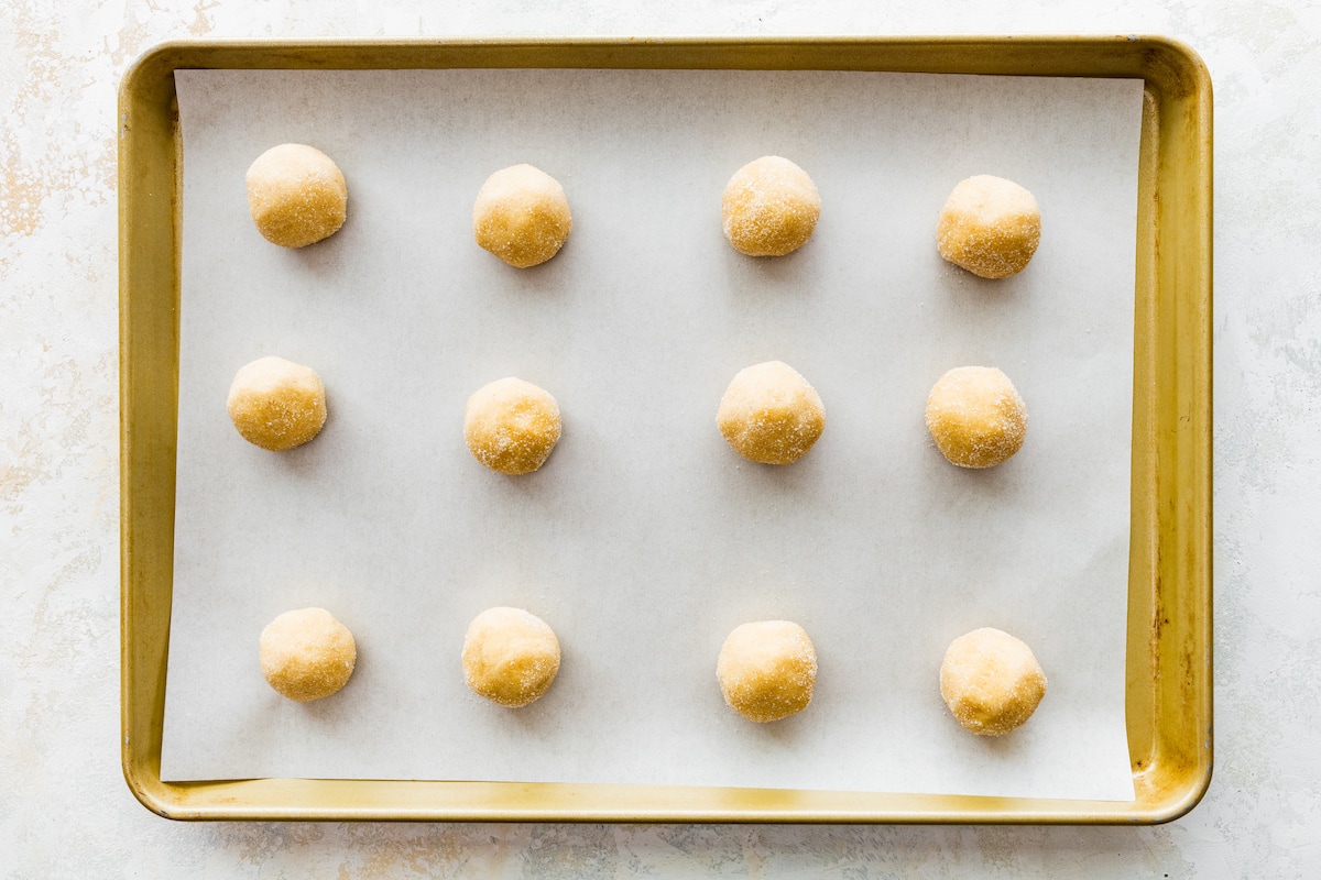 brown butter sugar cookie dough balls on baking sheet with parchment paper. 