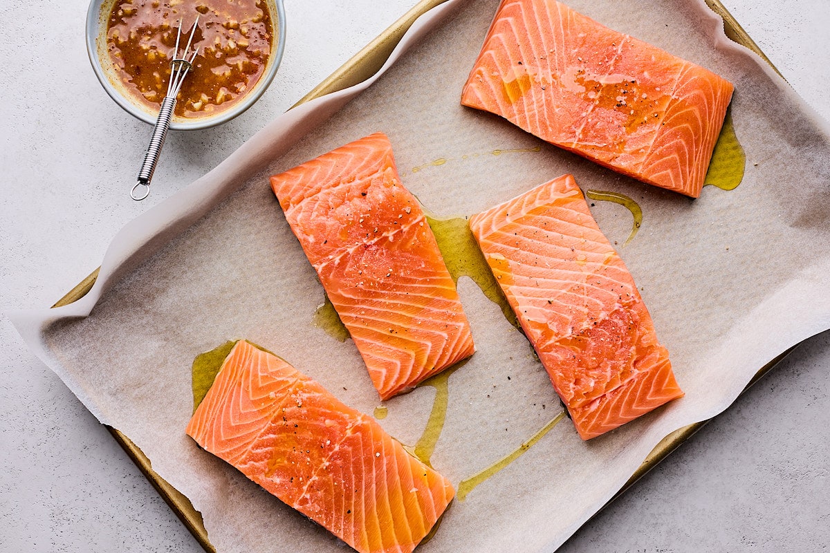 salmon fillets with drizzle of olive oil on baking sheet with parchment paper. 