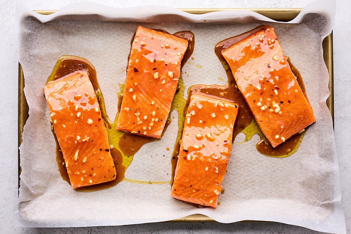salmon fillets with honey mustard glaze on baking sheet with parchment paper. 