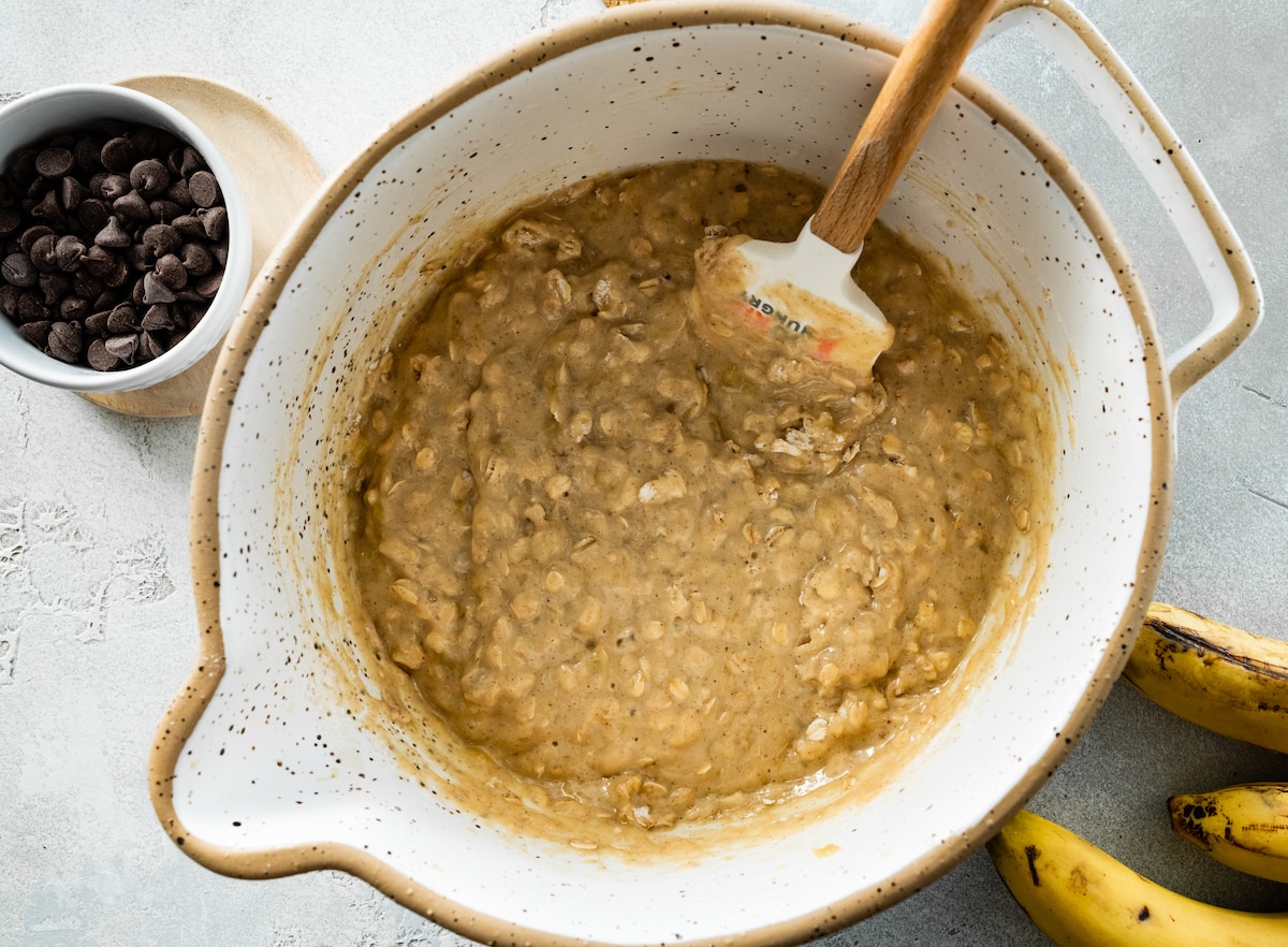 banana oatmeal muffin batter in mixing bowl with spatula. 