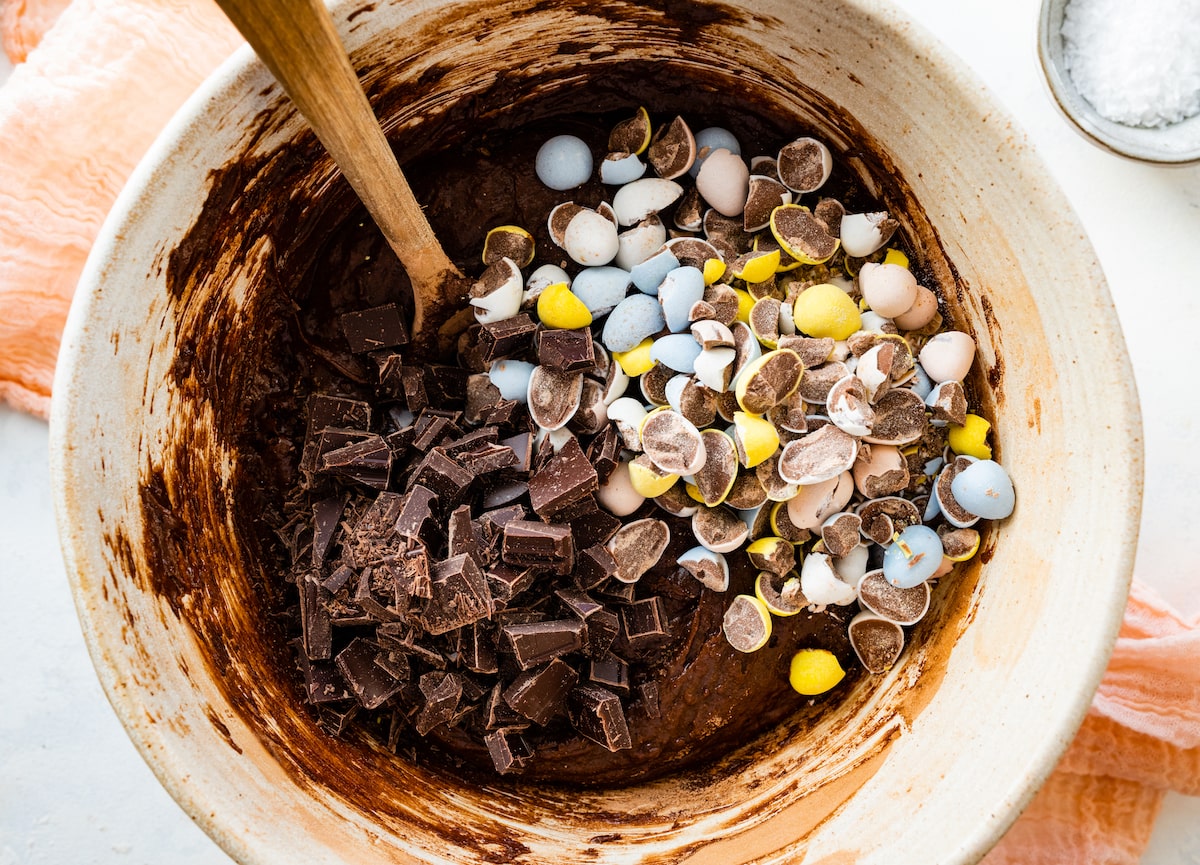 brownie batter in bowl with chocolate chunks and Cadbury mini eggs. 