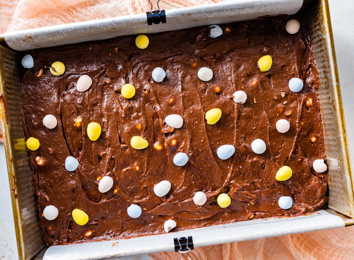 brownie batter in pan with Cadbury mini eggs. 