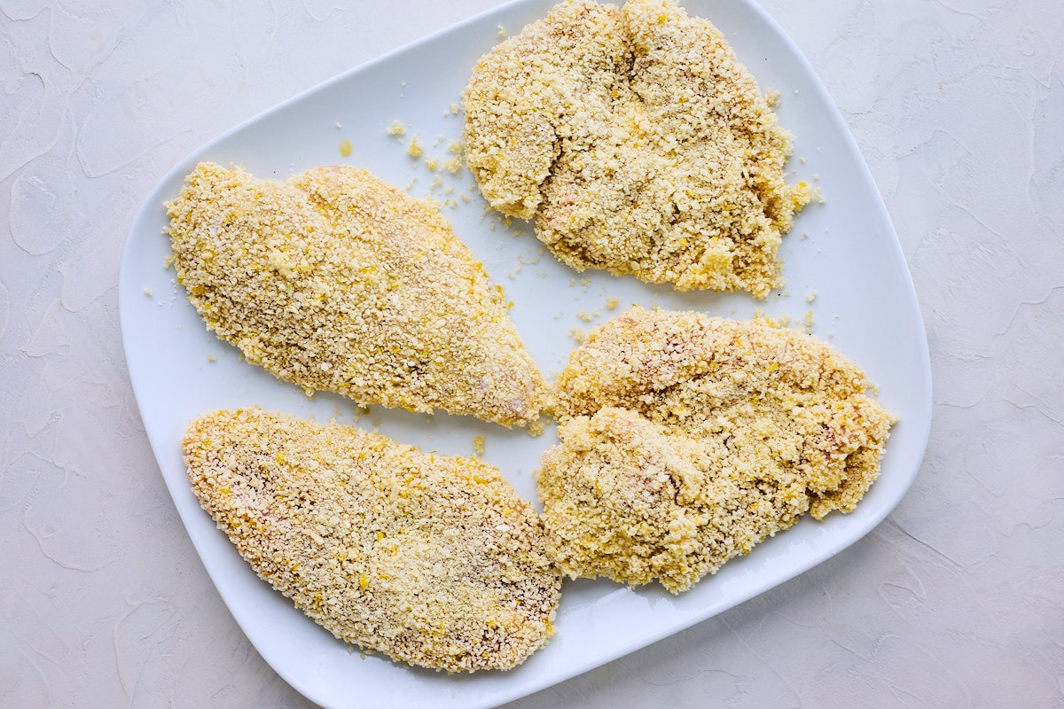 chicken breasts coated in flour and panko on plate to make chicken piccata. 