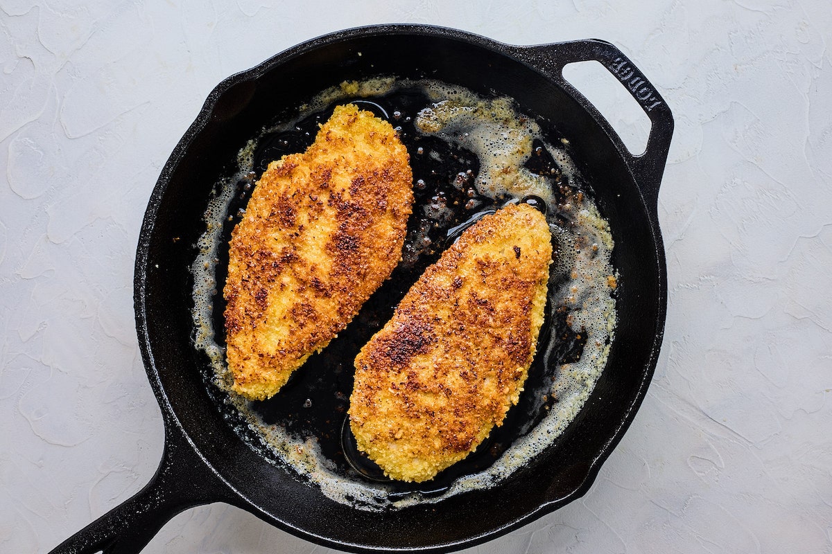 chicken breasts frying in cast iron skillet. 