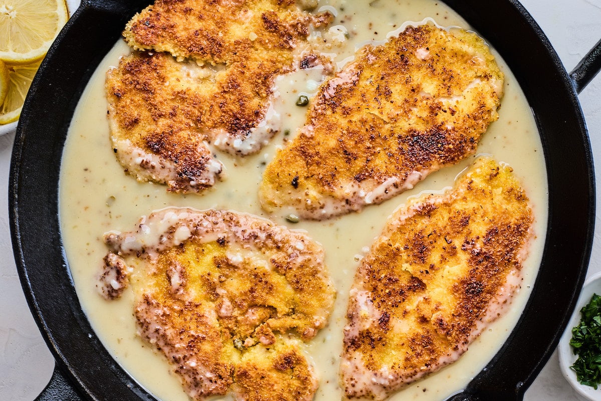 crispy chicken breasts in lemon butter sauce in cast iron skillet. 