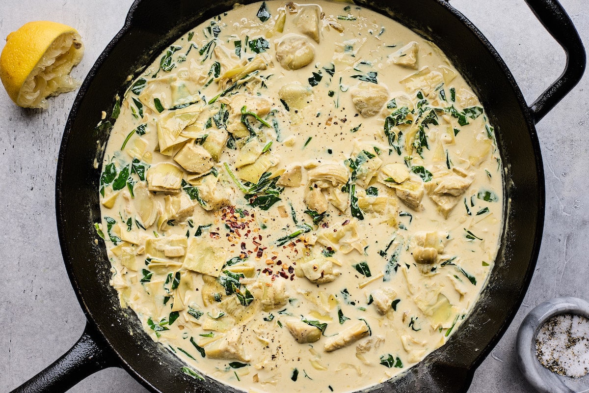 creamy spinach artichoke sauce in cast iron skillet. 