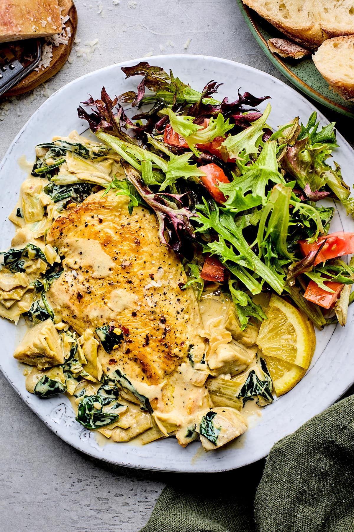 spinach artichoke chicken on plate with salad. 