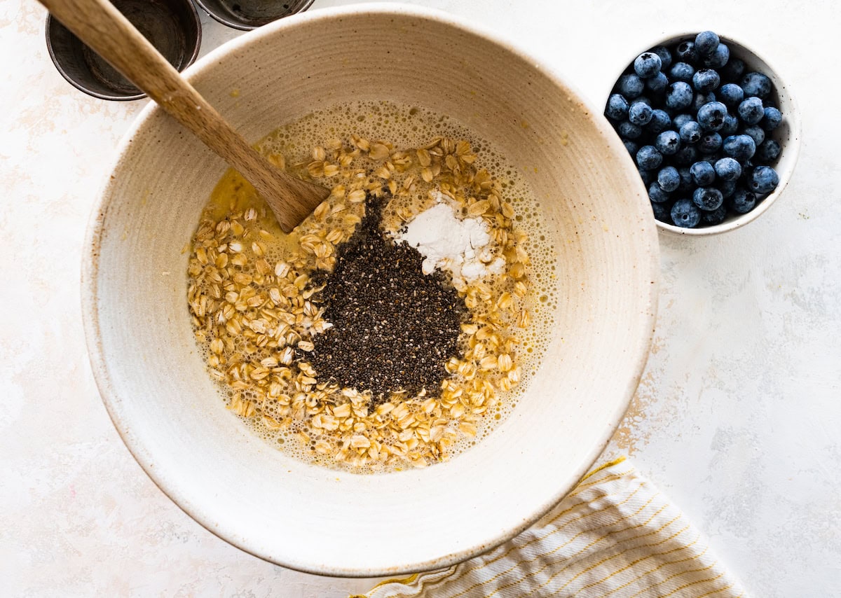 lemon blueberry baked oatmeal being mixed together in mixing bowl with wooden spoon. 