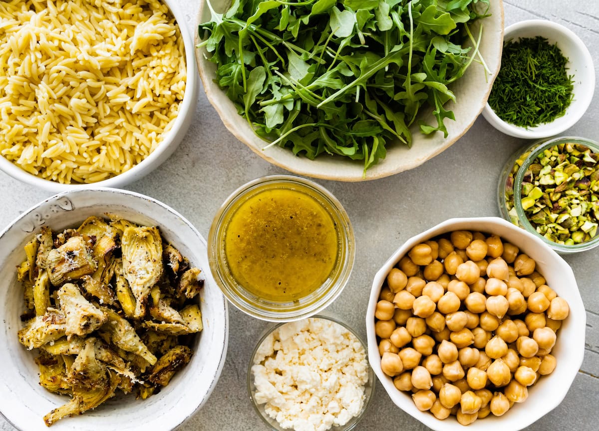 ingredients in bowls to make roasted artichoke chickpea orzo salad. 