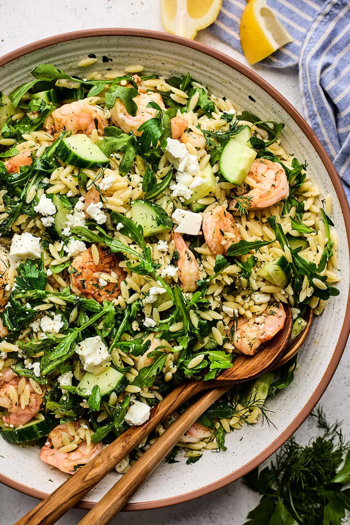 shrimp orzo salad in serving bowl with serving spoons. 