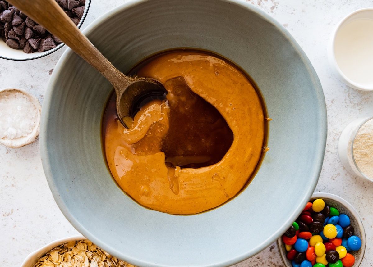 peanut butter, honey, and vanilla in mixing bowl with wooden spoon. 