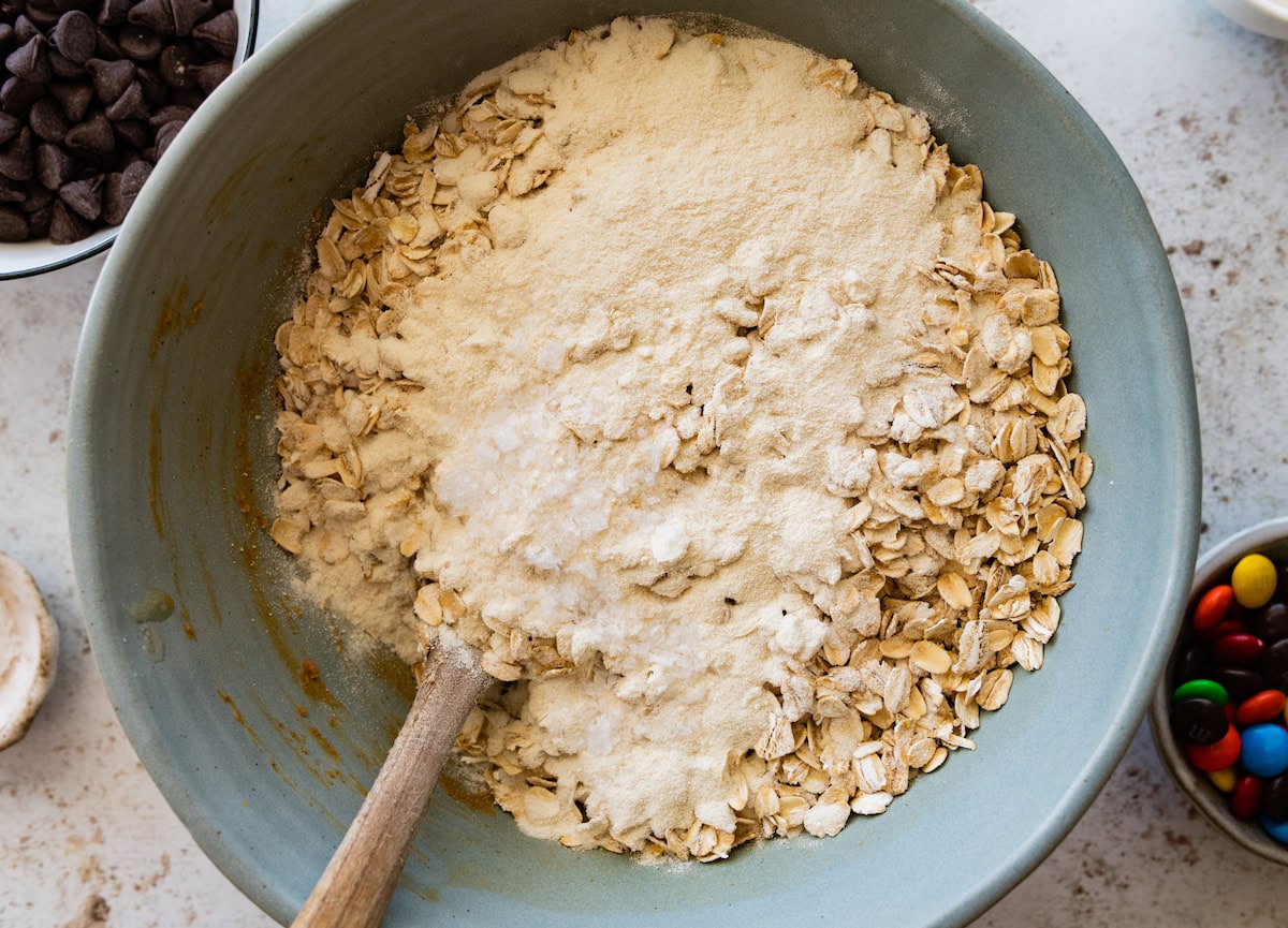 oats and protein powder in mixing bowl with wooden spoon.