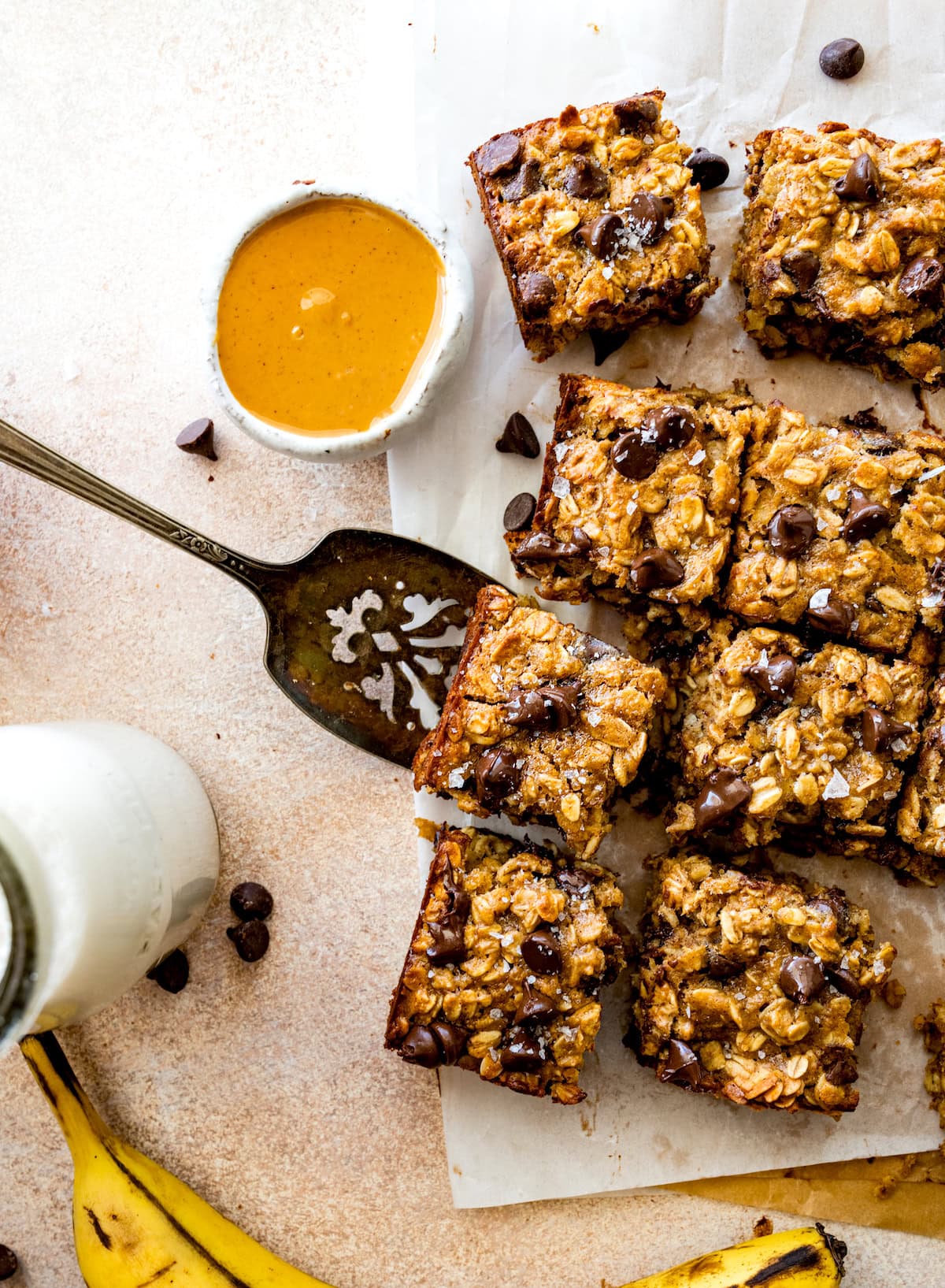peanut butter banana oatmeal bars with chocolate chips cut into squares on parchment paper. 