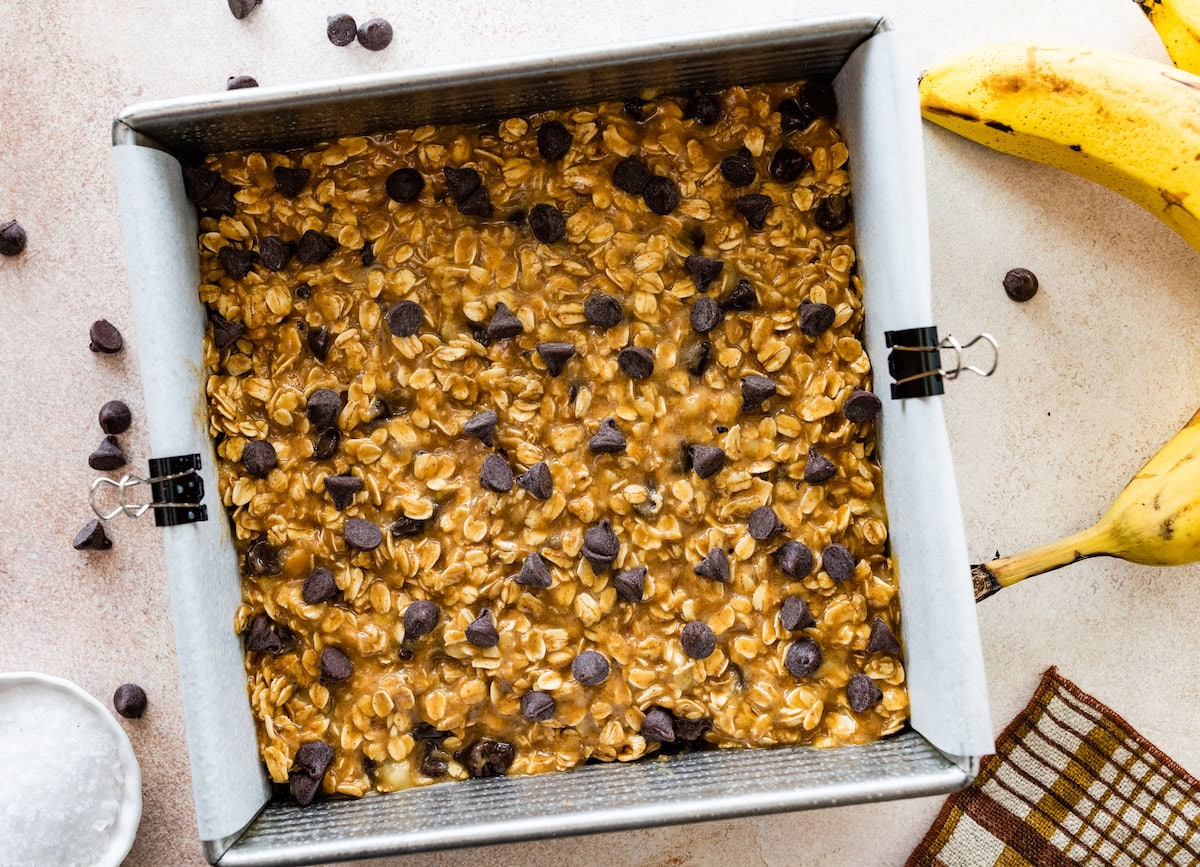 peanut butter banana oatmeal bars in pan with chocolate chips on top ready to be baked. 