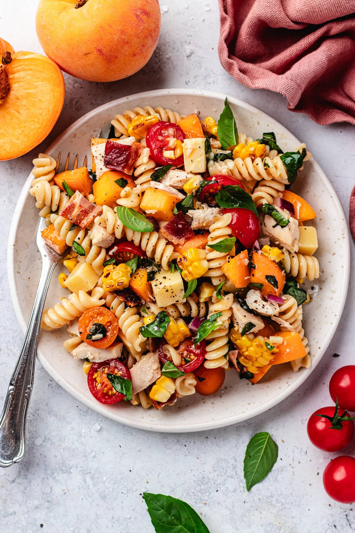 chicken bacon peach pasta salad with hot honey dressing on plate with fork. 