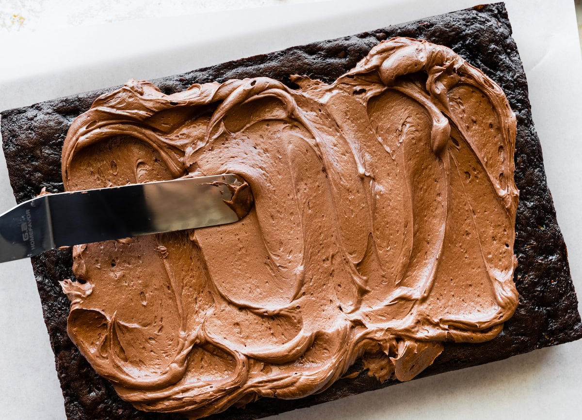 chocolate frosting being spread on top of chocolate zucchini cake. 