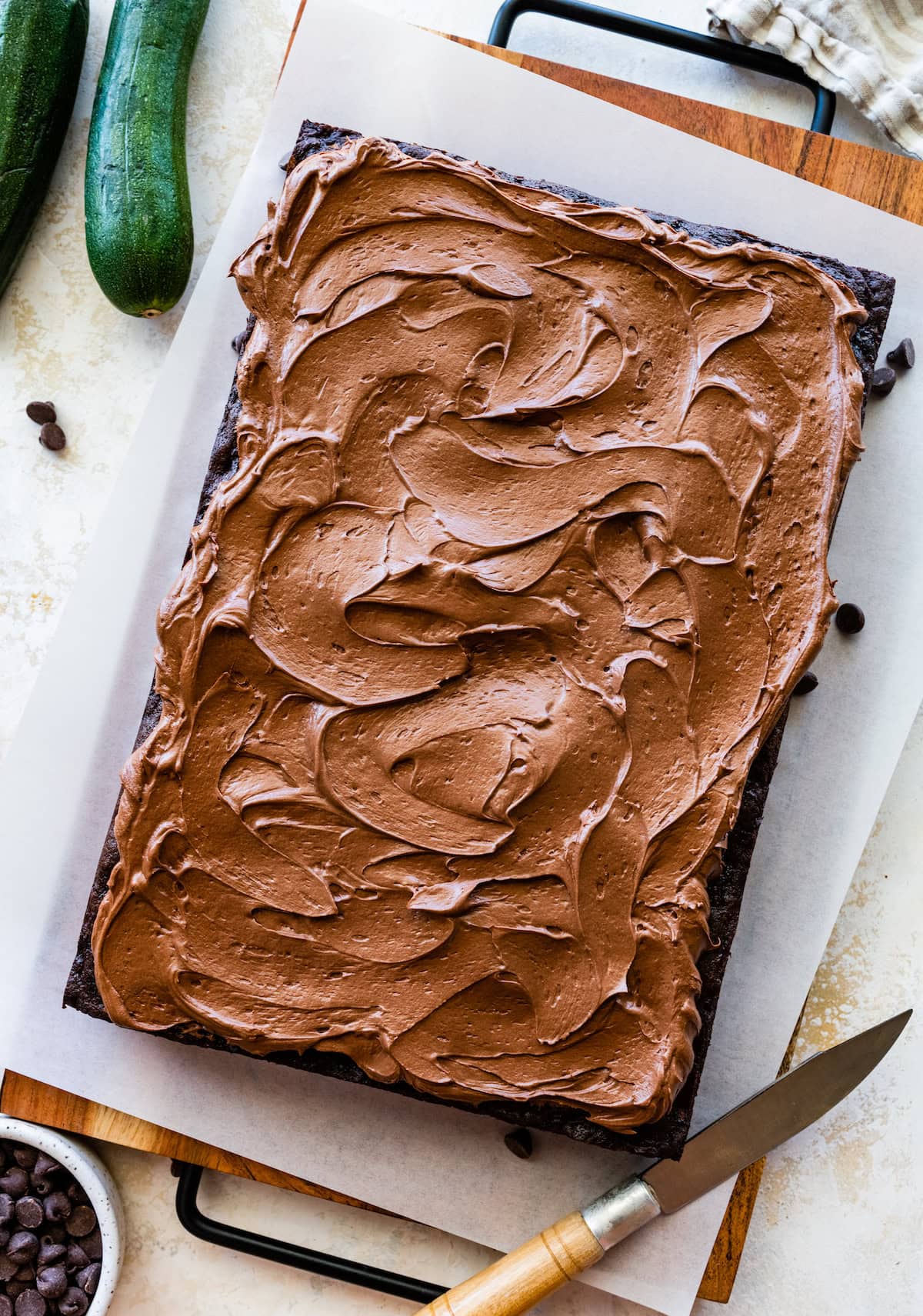 chocolate cake with chocolate frosting with knife on board. 