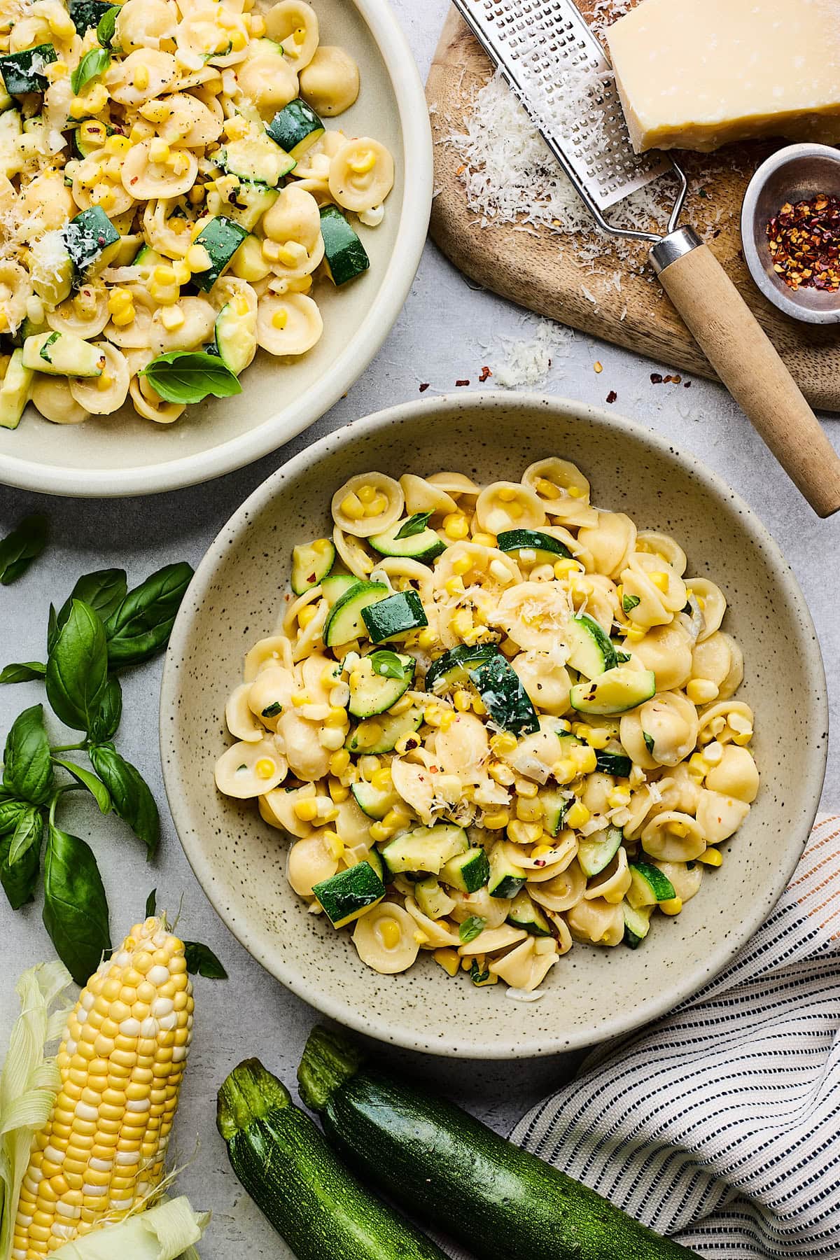 creamy zucchini corn pasta in bowl with basil and parmesan cheese. 