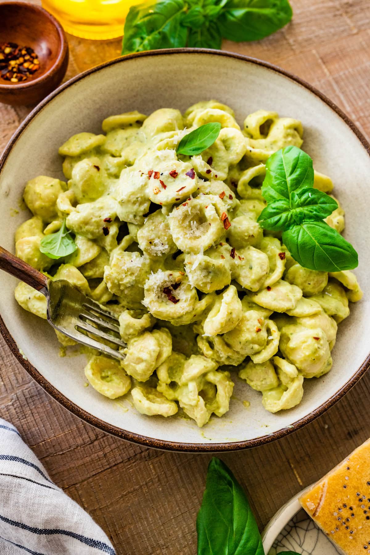 cottage cheese creamy pesto pasta with fresh basil, parmesan cheese, crushed red pepper flakes in bowl with fork. 