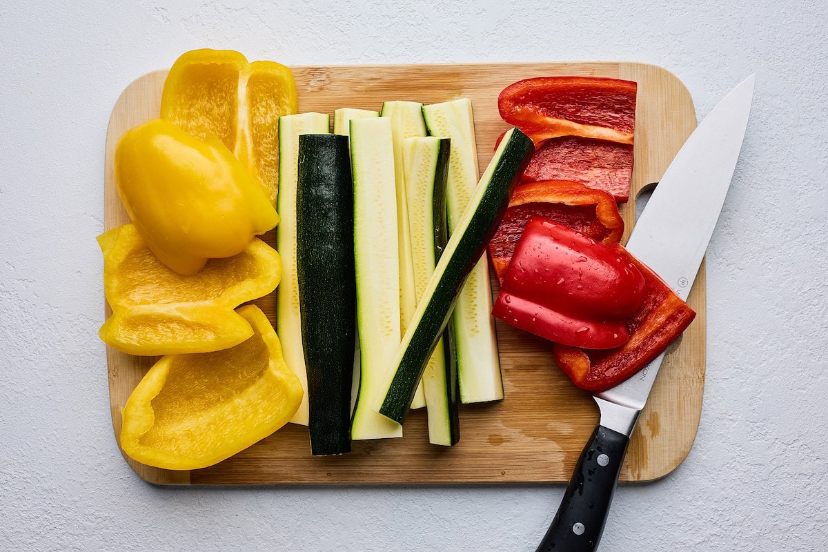 bell peppers and zucchini on wood cutting board with knife. 