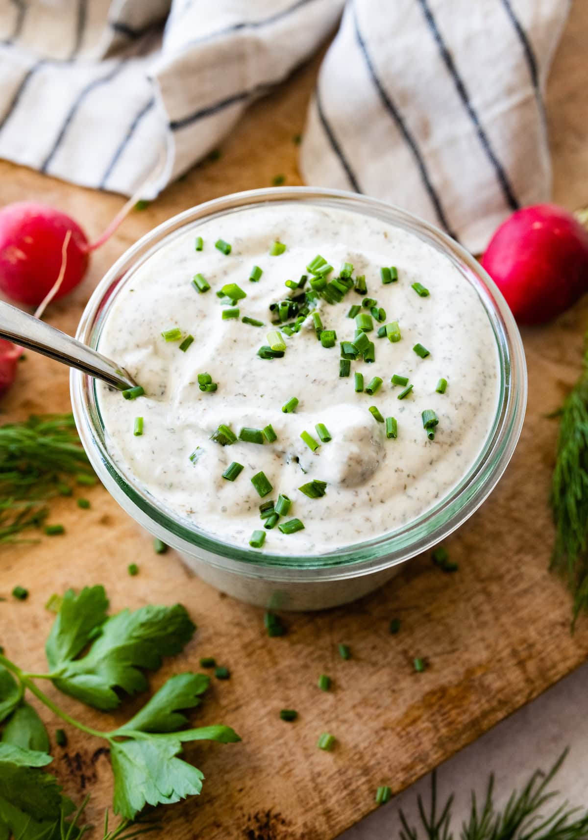 homemade ranch dip with fresh chives in glass bowl with spoon. 