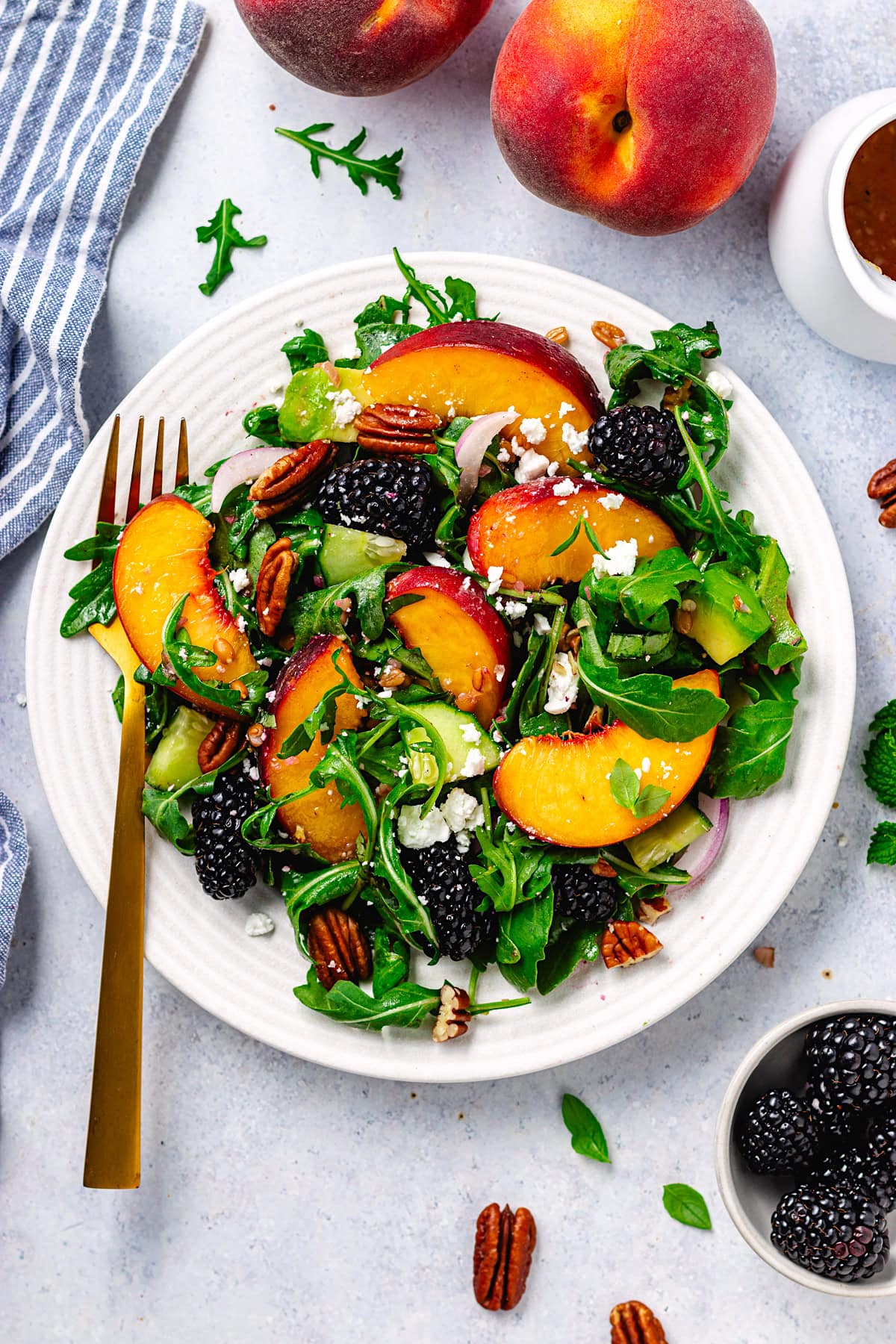 blackberry peach arugula salad on plate with fork. 