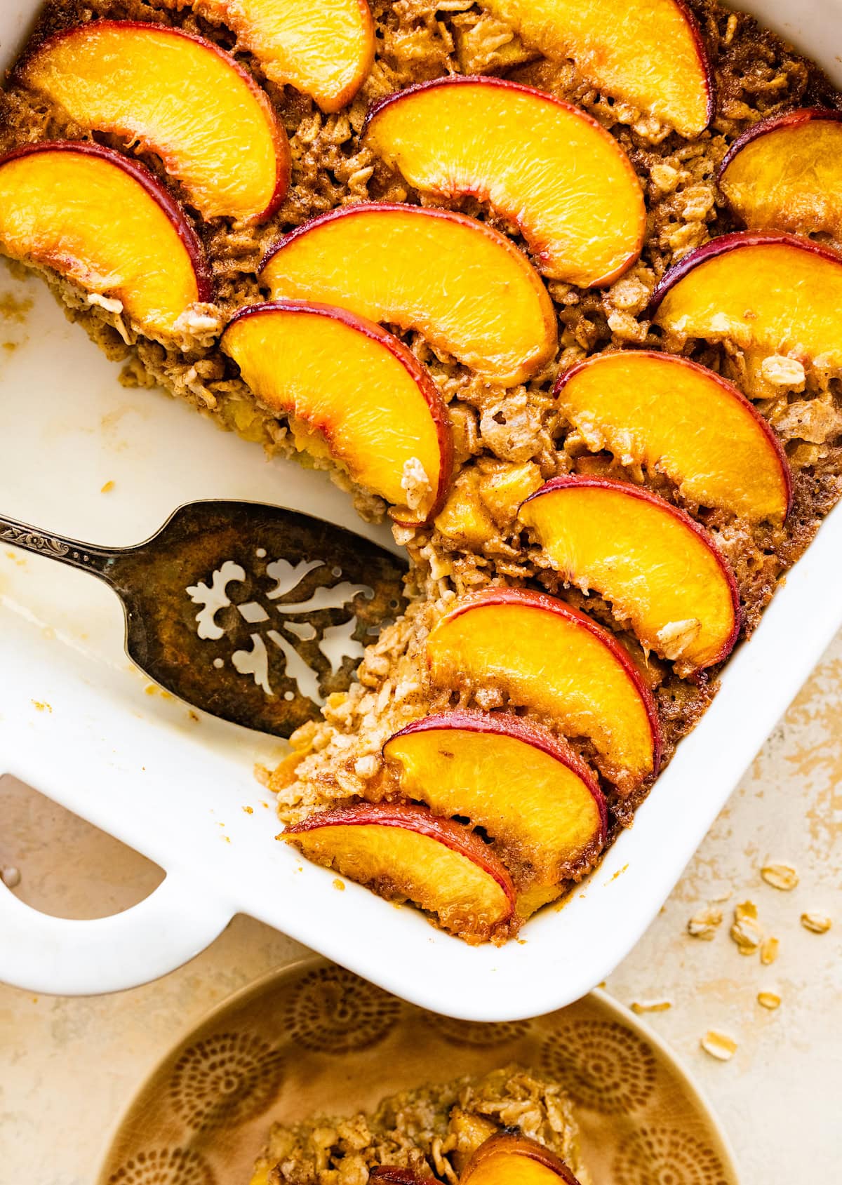 peach baked oatmeal in pan with server. 