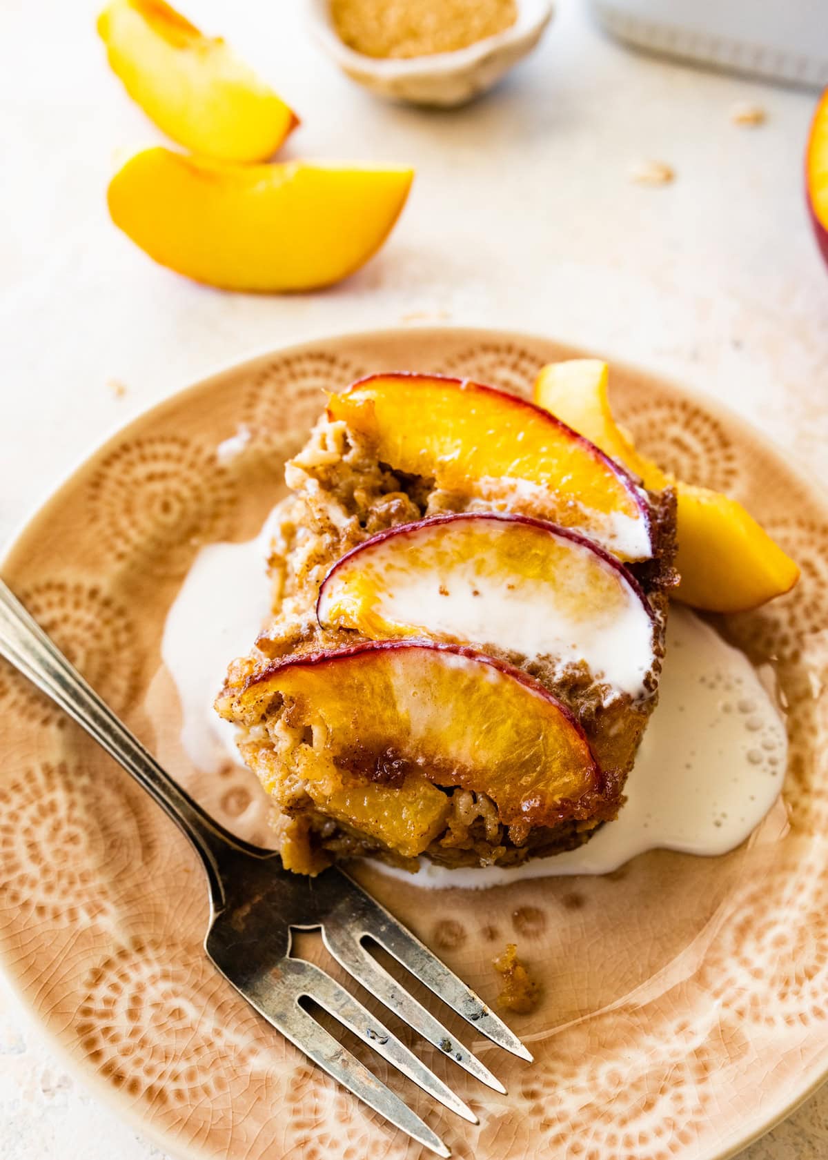 peach baked oatmeal on plate with a drizzle of heavy cream. 