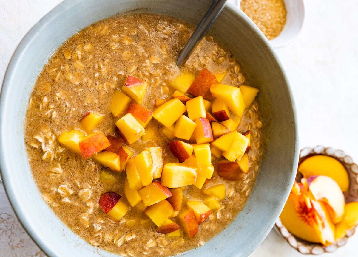 chopped peaches being stirred into oatmeal mixture.