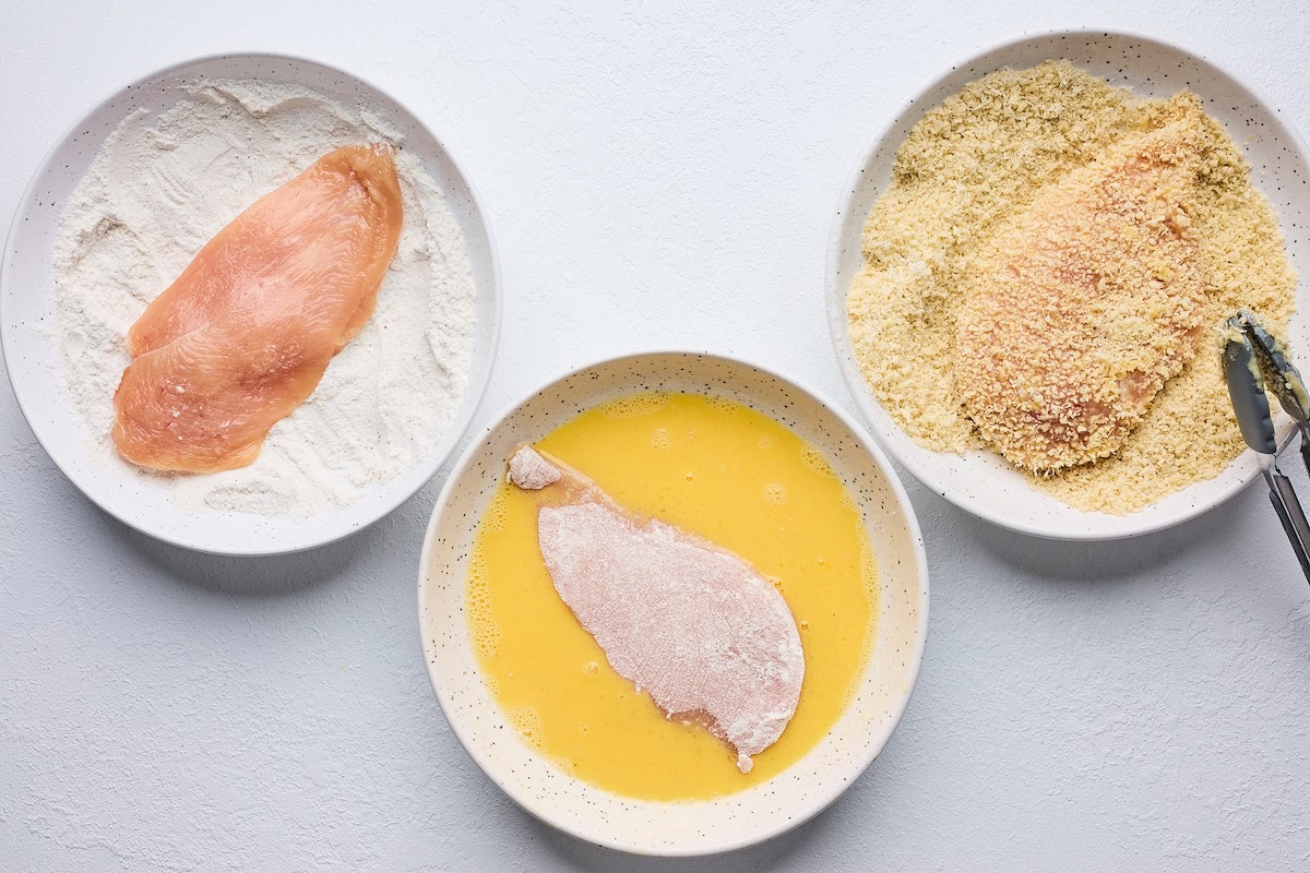 chicken breasts on plates with flour, egg, and panko. 