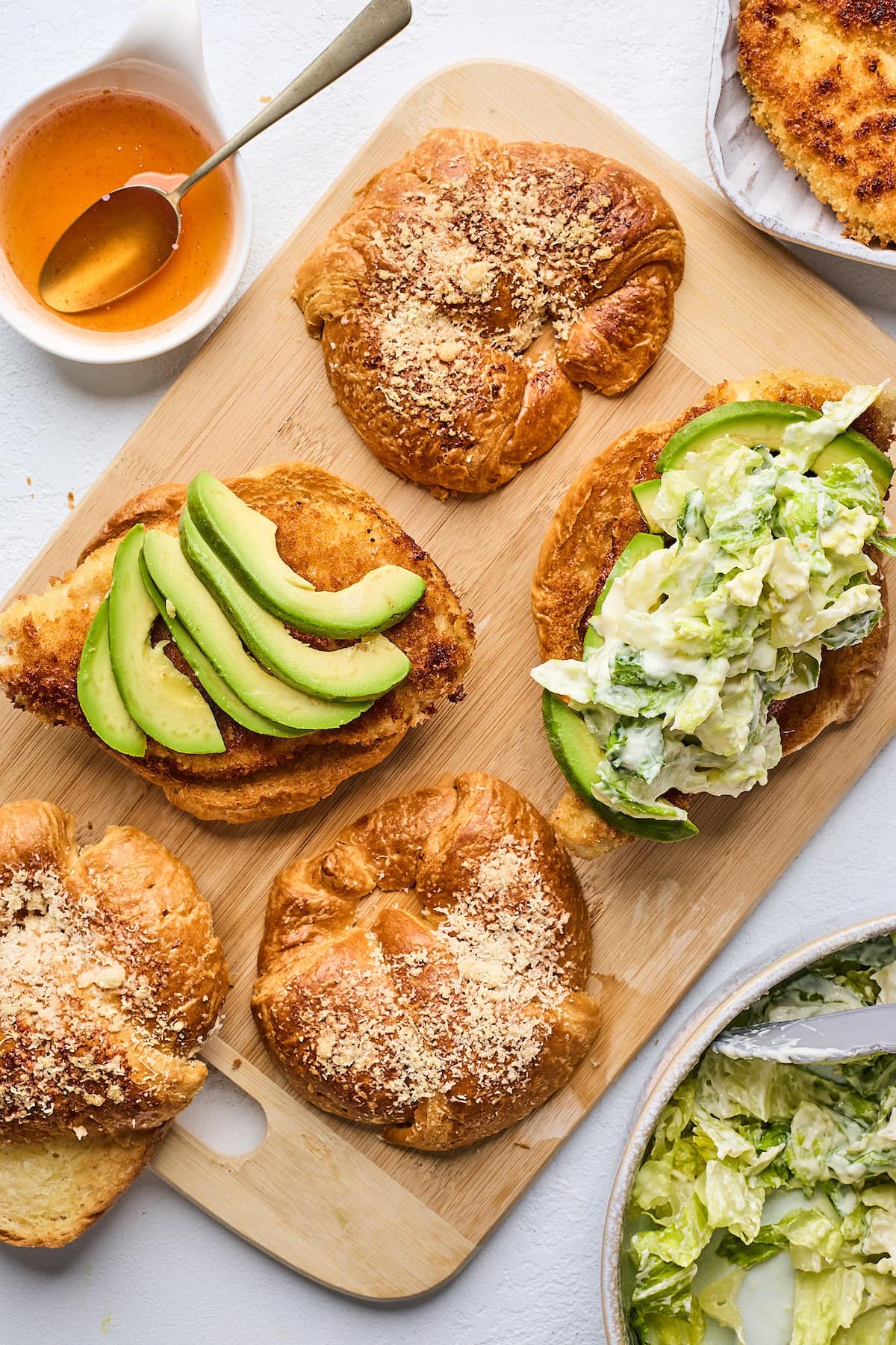 crispy chicken croissant sandwiches with romaine lettuce in creamy lemon dressing and avocado slices. 