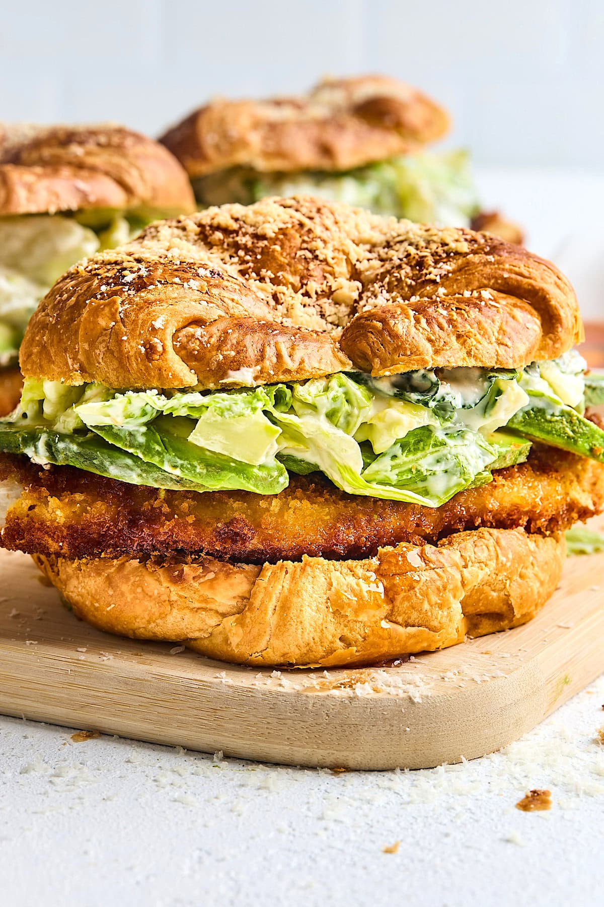 crispy chicken croissant sandwich with lettuce, avocado, and Parmesan cheese. 