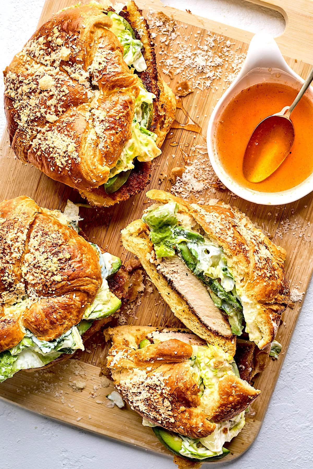 crispy chicken croissant sandwiches with romaine lettuce, avocado, Parmesan cheese, and hot honey. 