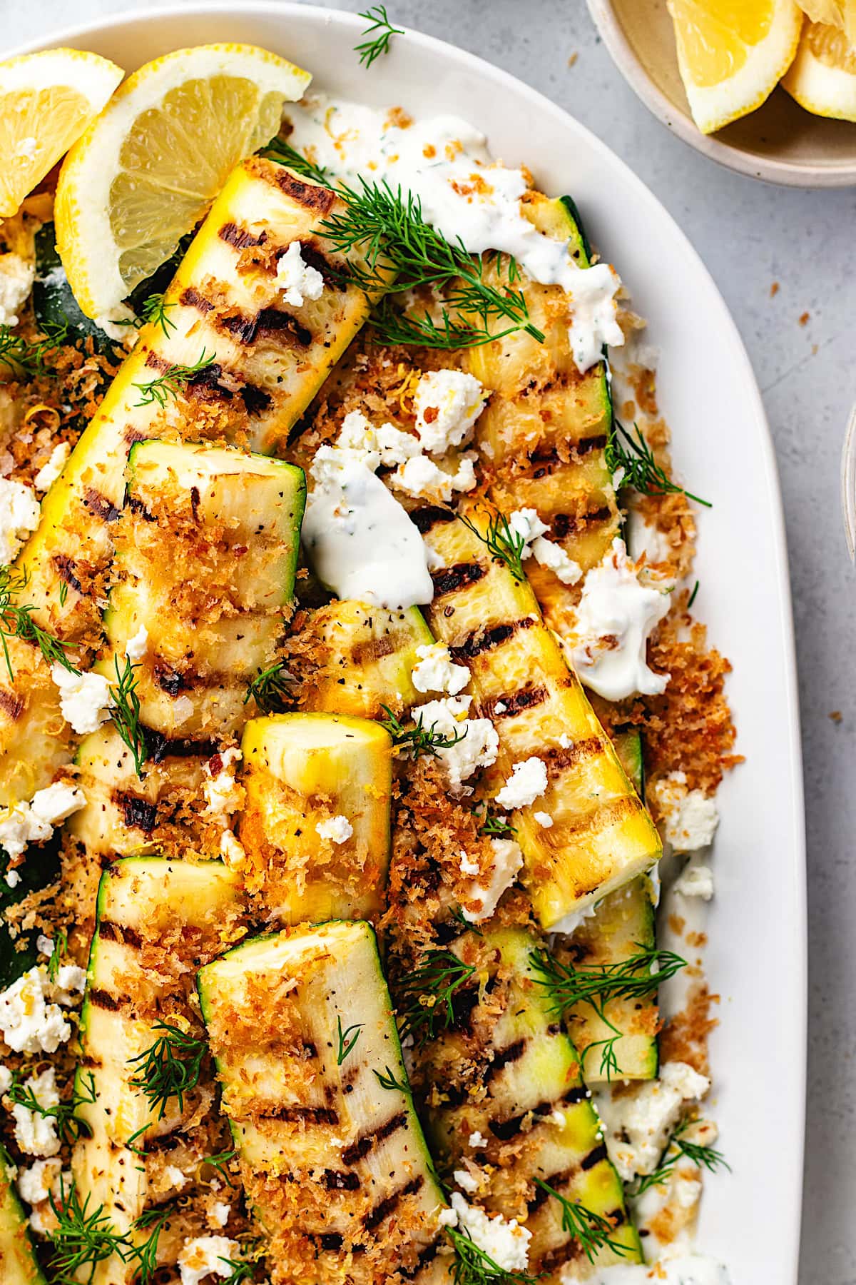 close up of grilled zucchini salad with creamy greek yogurt feta spread and garlic breadcrumbs. 